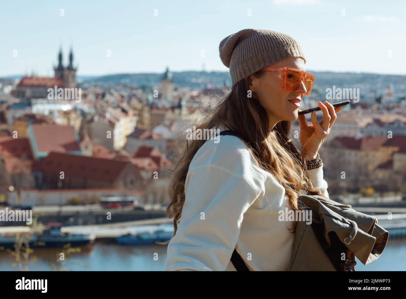 Jeune touriste solo en sweat-shirt blanc à Prague République tchèque écoutant un audioguide sur l'application pour smartphone. Banque D'Images