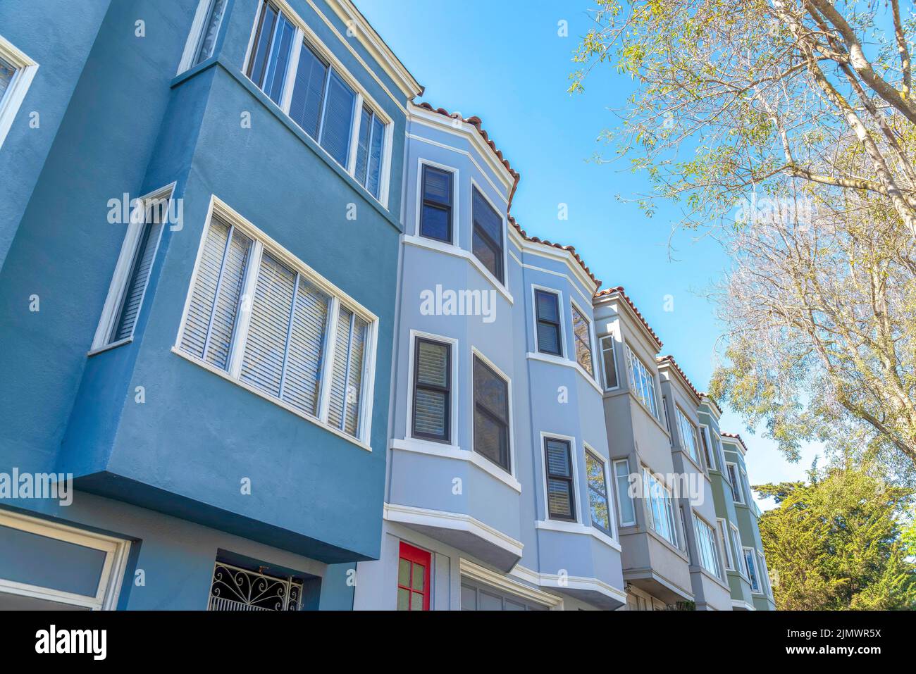 Façade extérieure des maisons de ville dans une rangée avec différentes couleurs de mur à San Francisco, Californie. Maisons de ville avec fenêtres en forme d'arc et de baie et vue à angle bas Banque D'Images