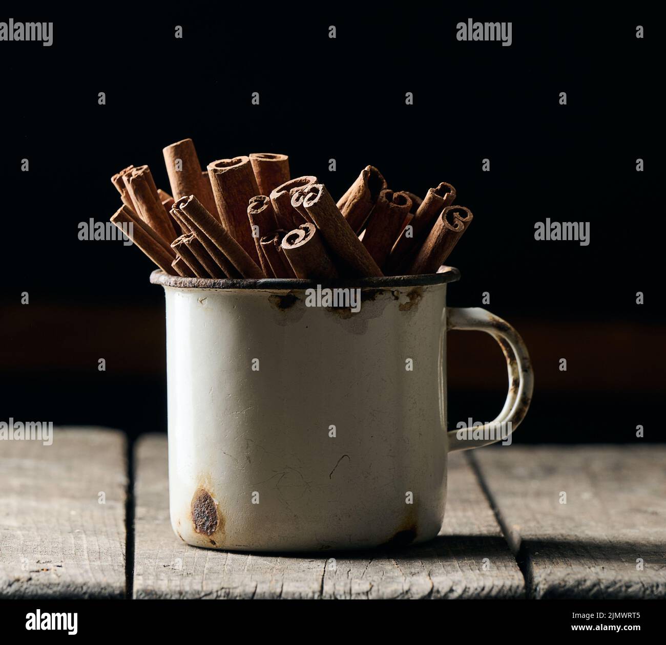 Bâtonnets de cannelle brun sec dans une vieille tasse en métal, épice culinaire Banque D'Images