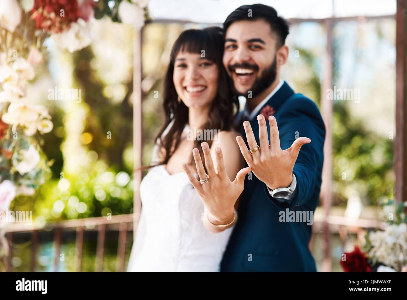 Nous venons de devenir M. et Mme un jeune couple affectueux et jeune jeune jeune couple qui a fait clignoter leurs anneaux de mariage tout en étant debout à l'extérieur le jour de leur mariage. Banque D'Images