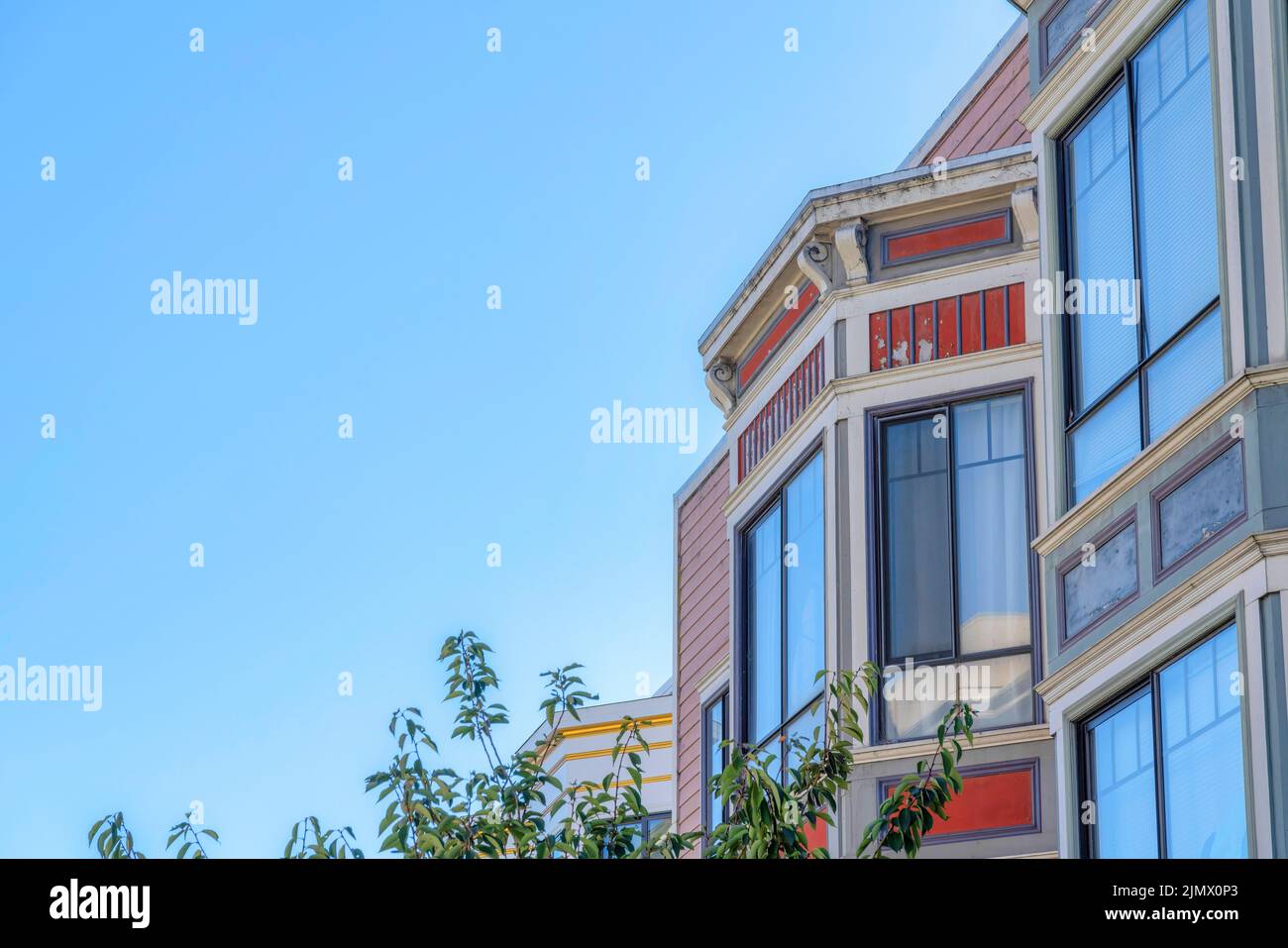 Fenêtres en verre réfléchissant d'une maison à San Francisco, Californie. Maison résidentielle avec des panneaux latéraux en bois d'orange rouge et vue sur les feuilles d'un arbre Banque D'Images