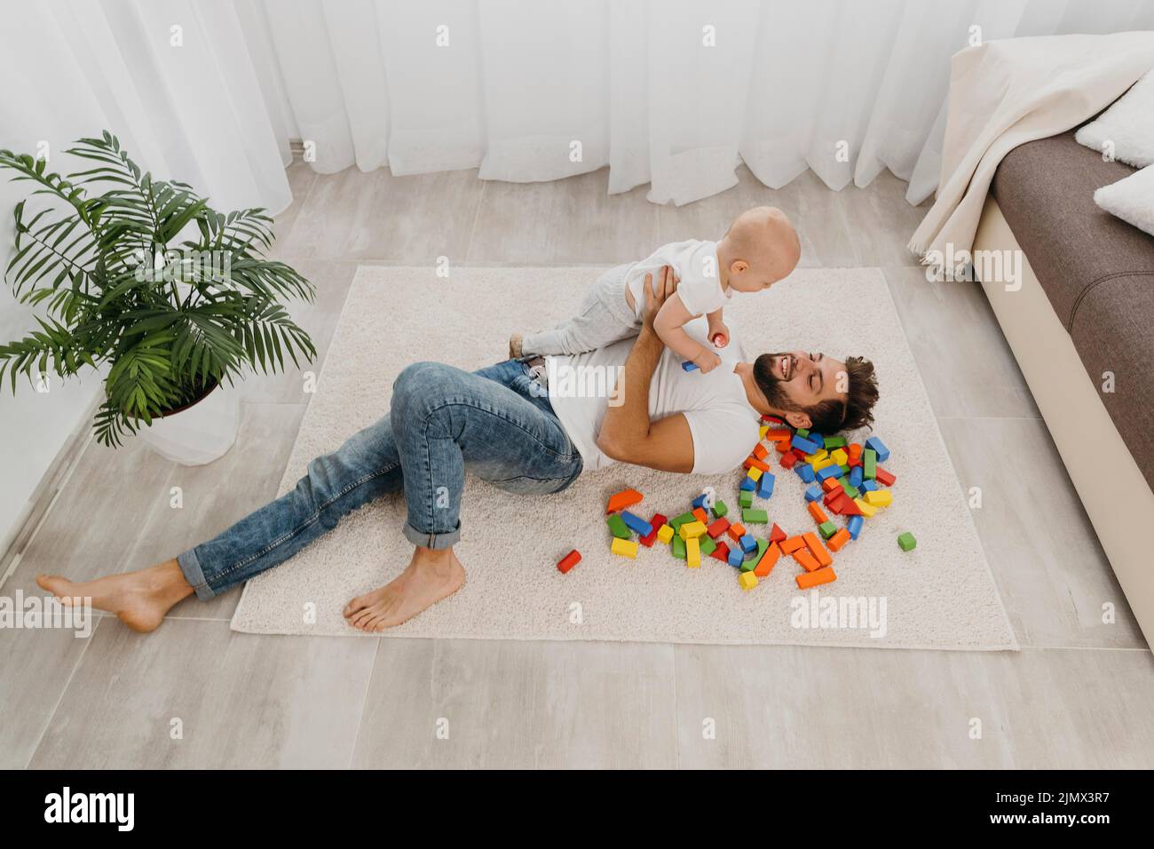 Père grand angle jouant au sol à la maison avec bébé Banque D'Images