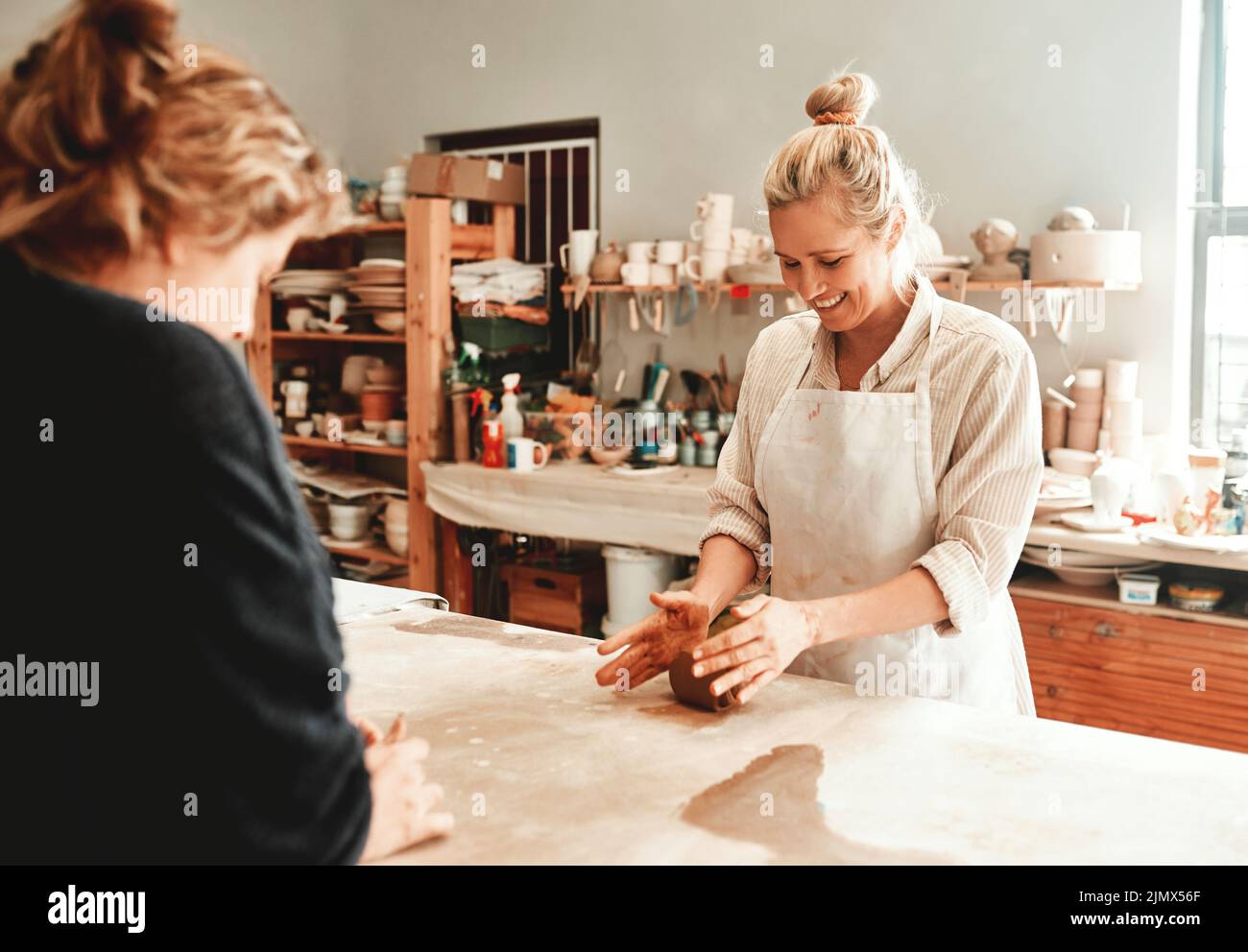 Vous ne regretterez pas de vous joindre à mes cours de poterie. Deux artisans travaillent ensemble dans un atelier de poterie. Banque D'Images