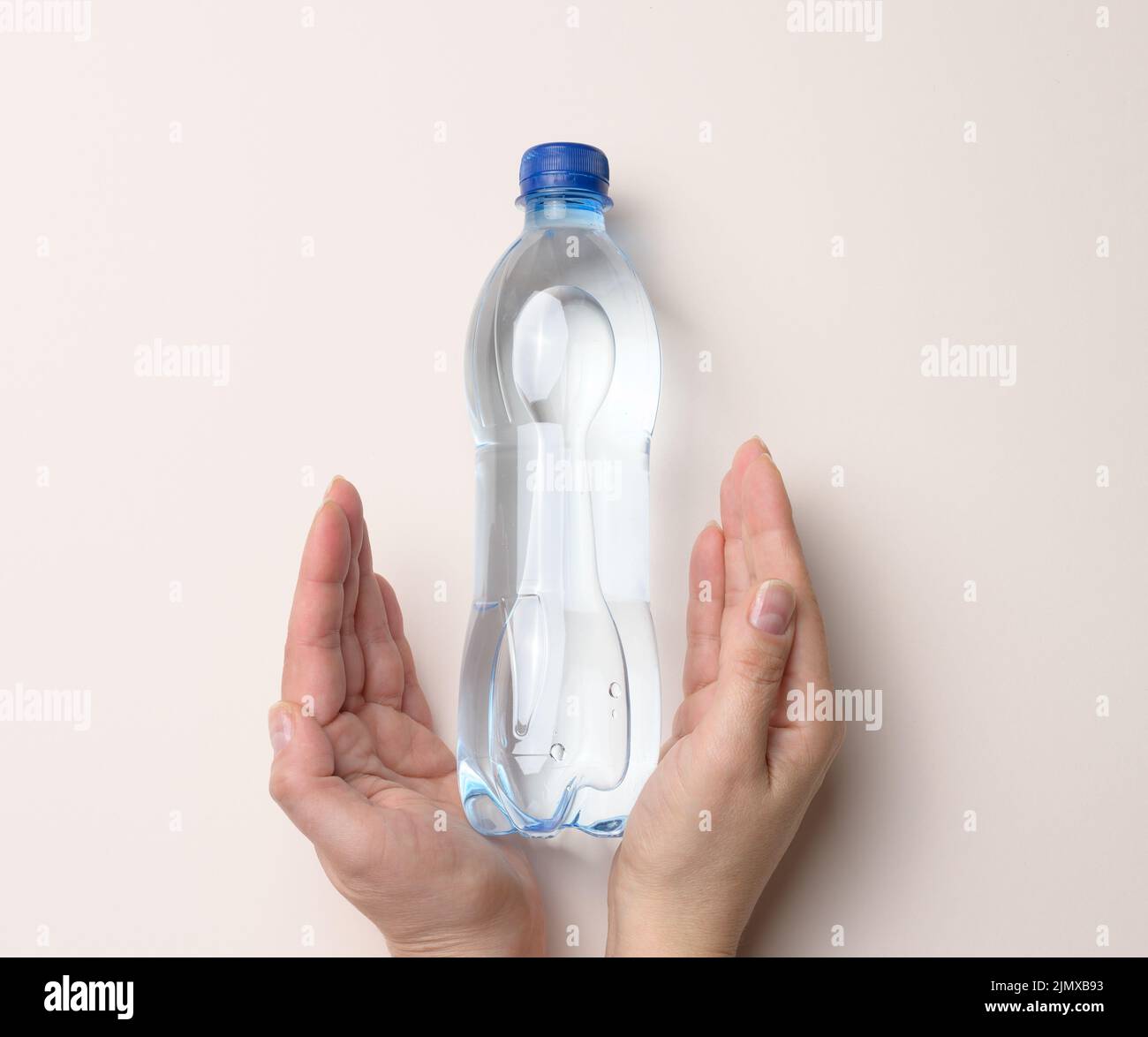Bouteille en plastique transparent avec eau potable sur fond beige Banque D'Images
