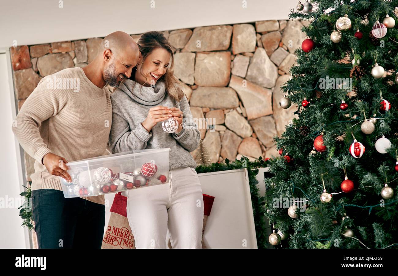 Je ne pense pas qu'il y avait un espace qui a laissé mon cher. Un couple joyeux d'âge moyen qui a placé des décorations sur un arbre de Noël à l'intérieur à la maison pendant la journée. Banque D'Images