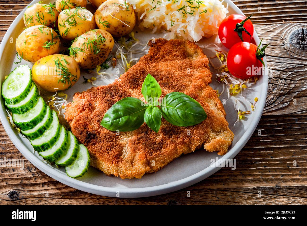 Côtelettes panées de porc enrobées de chapelure servie avec des pommes de terre et du chou Banque D'Images