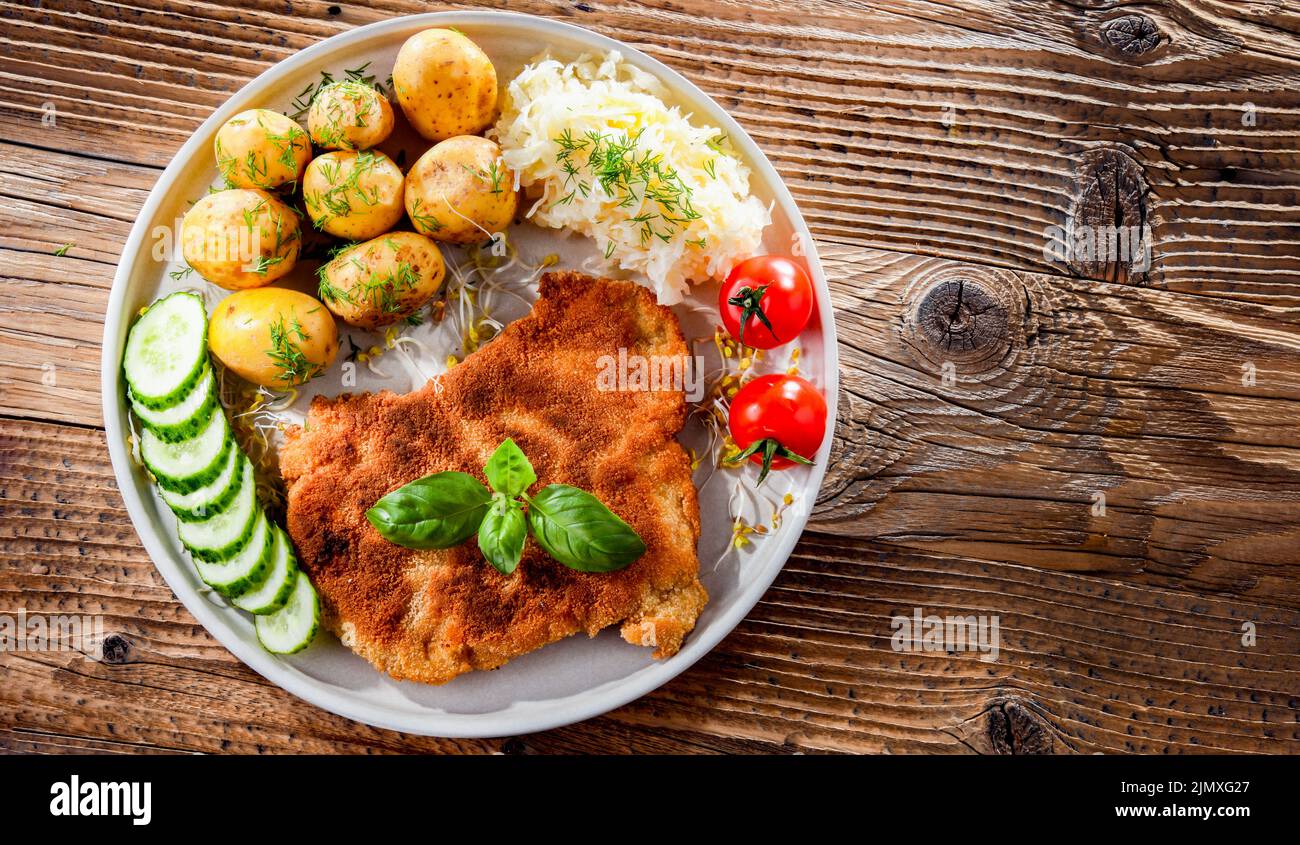 Côtelettes panées de porc enrobées de chapelure servie avec des pommes de terre et du chou Banque D'Images