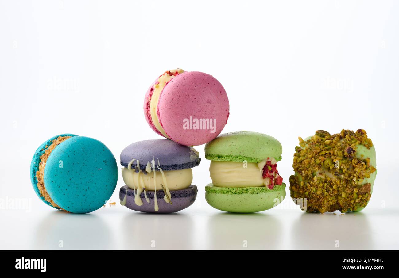 Gâteaux français ronds à base de macarons à la farine d'amandes sur fond blanc. Arôme framboise, pistache et lavande Banque D'Images