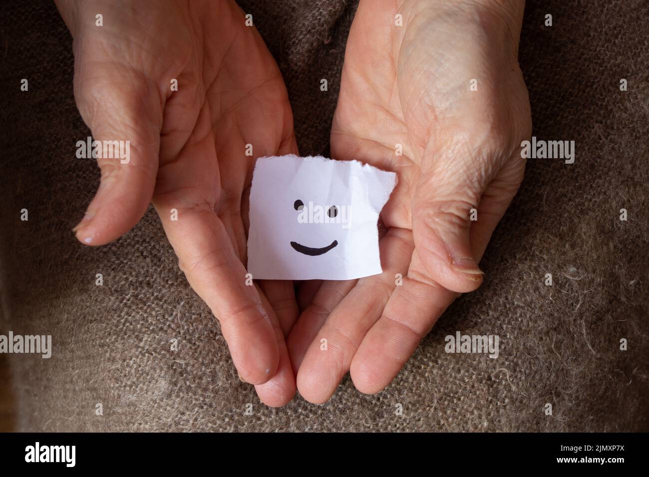 une émoticône gaie est dessinée sur un morceau de papier entre les mains d'une femme, une bonne humeur, de la joie et un sourire Banque D'Images