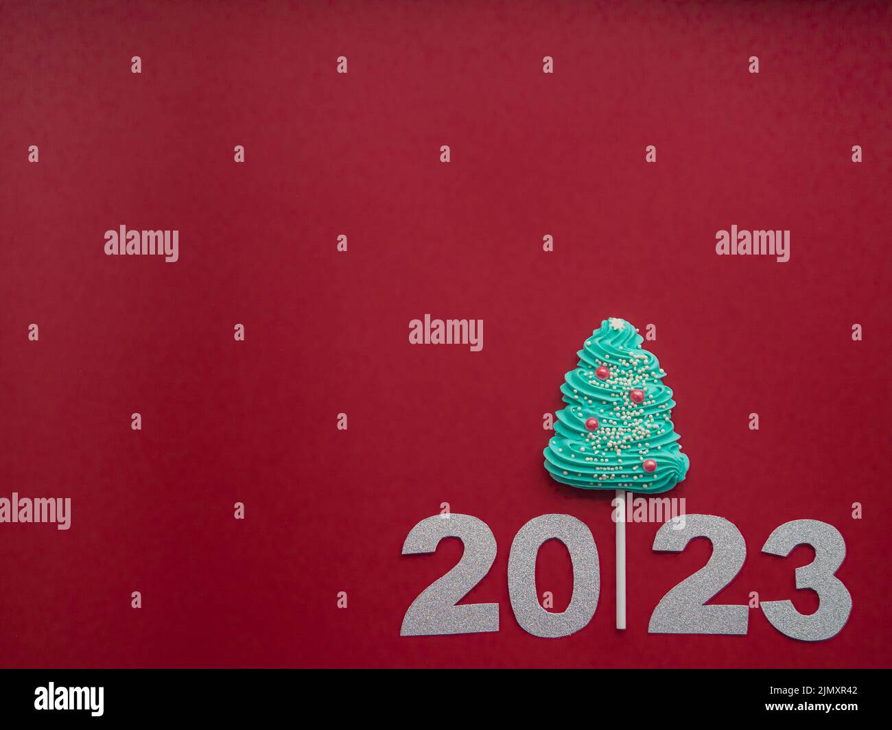 2023 et des bonbons bleus sous forme d'arbre de Noël sur fond rouge Banque D'Images