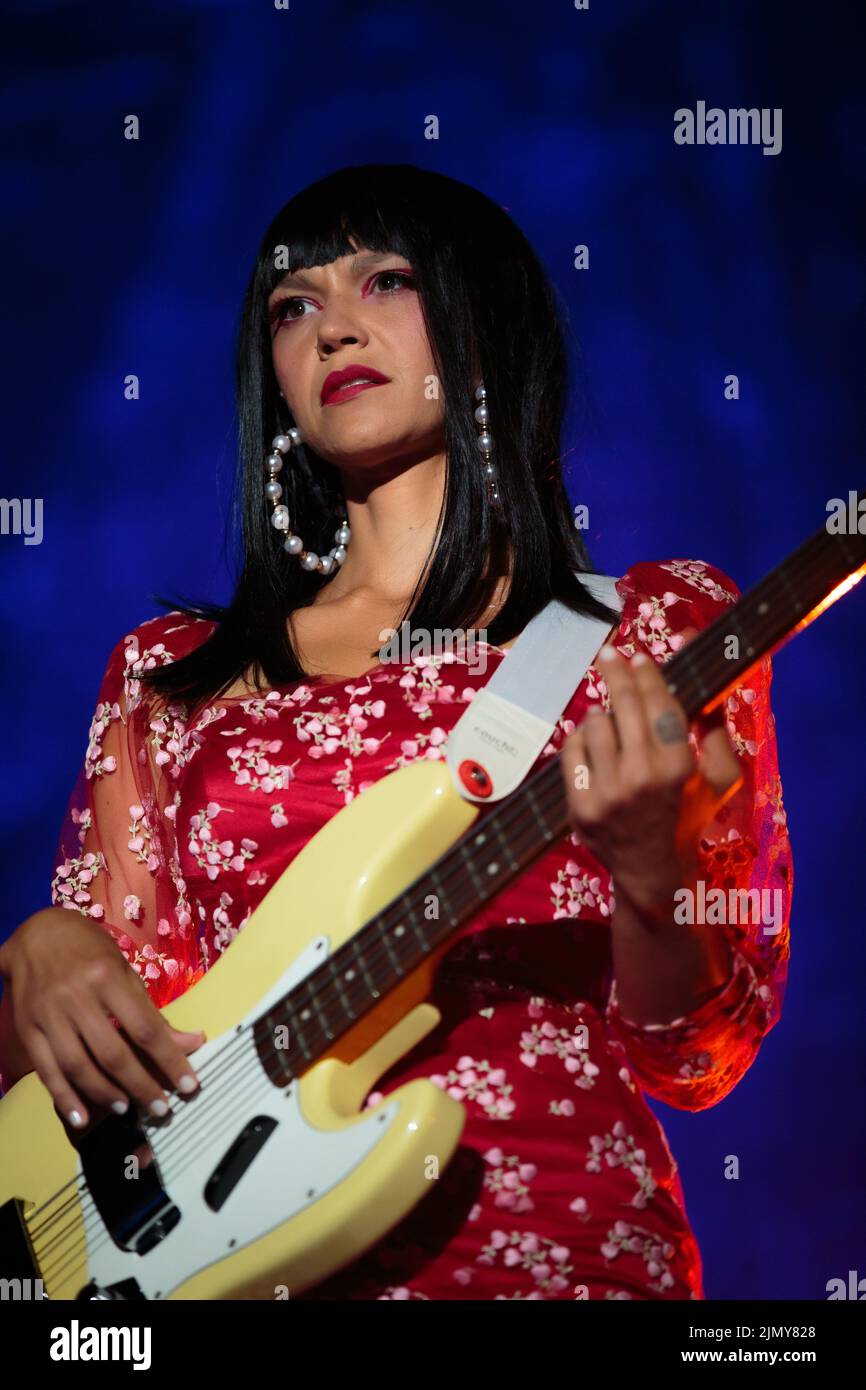 Bassiste Laura Lee de Khruangbin sur scène portant une petite robe à motif floral rouge avec des bas blancs Banque D'Images