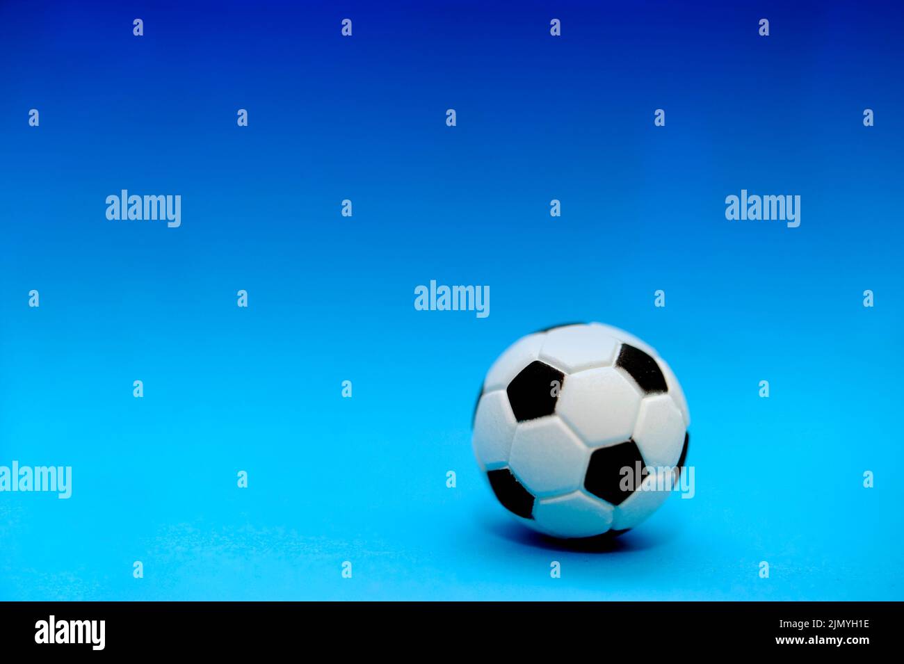 ballon de football miniature sur fond bleu Banque D'Images