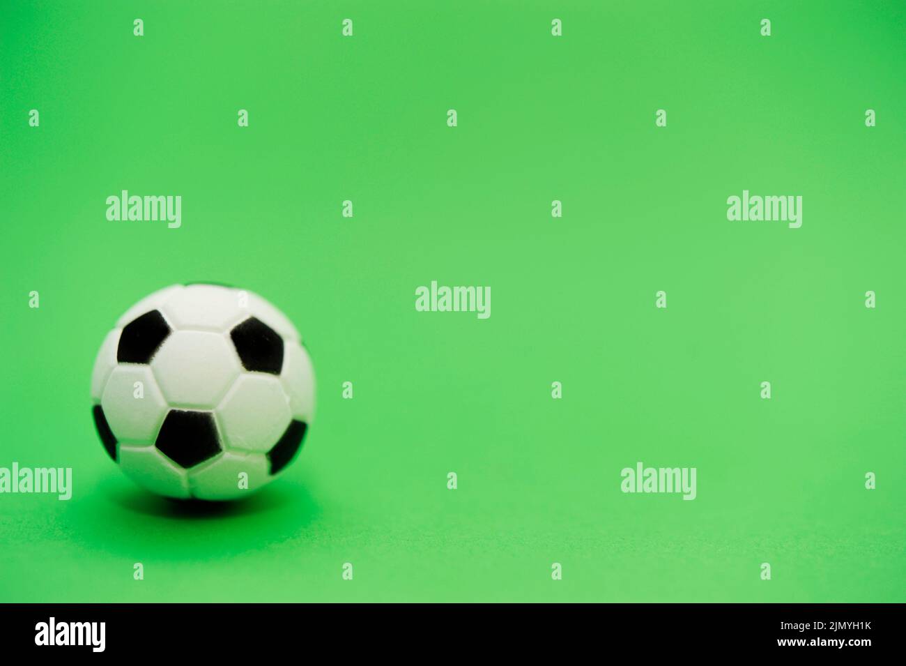 ballon de football miniature sur fond vert Banque D'Images