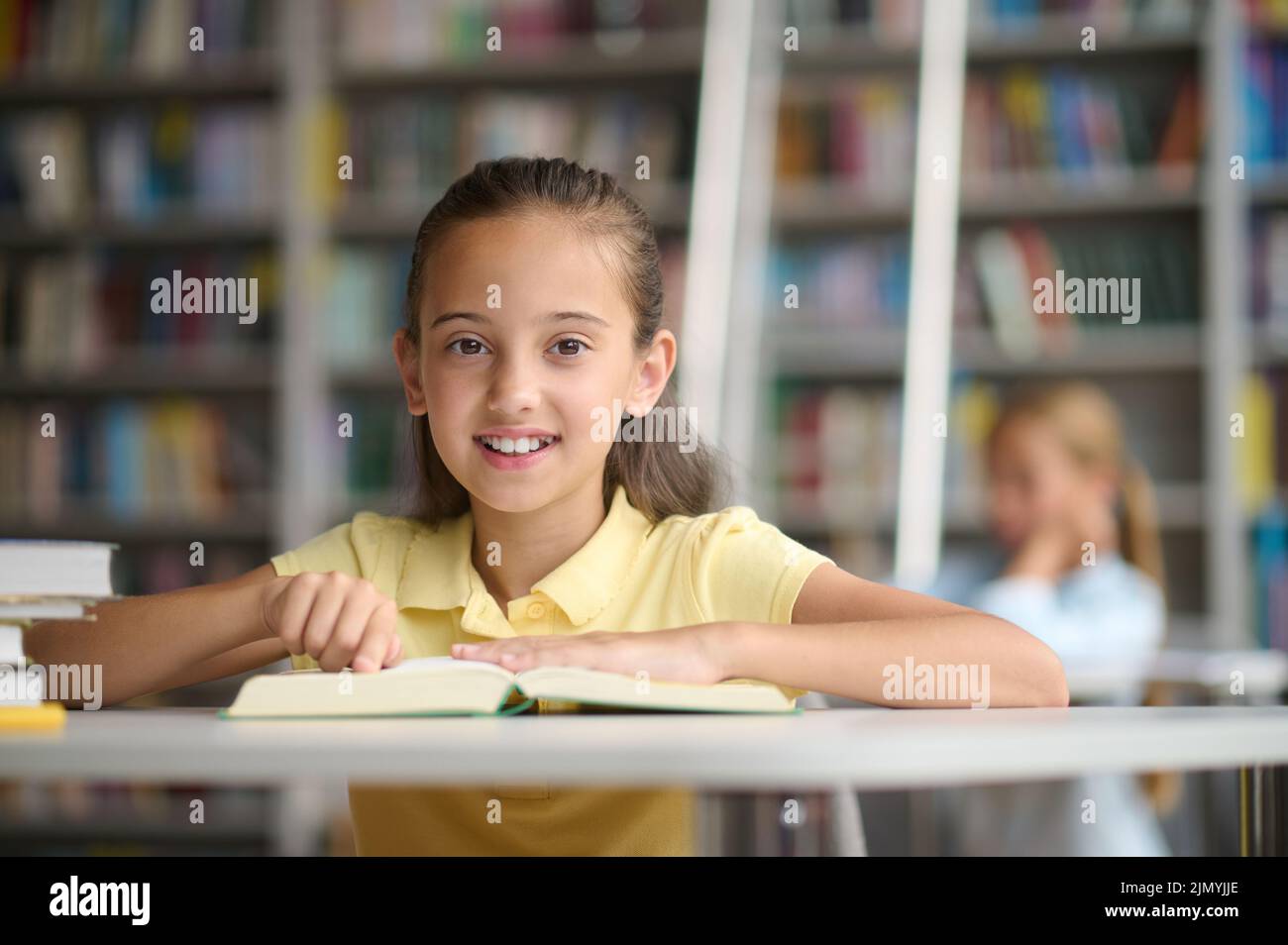 Écolière posant pour la caméra dans la salle de lecture Banque D'Images