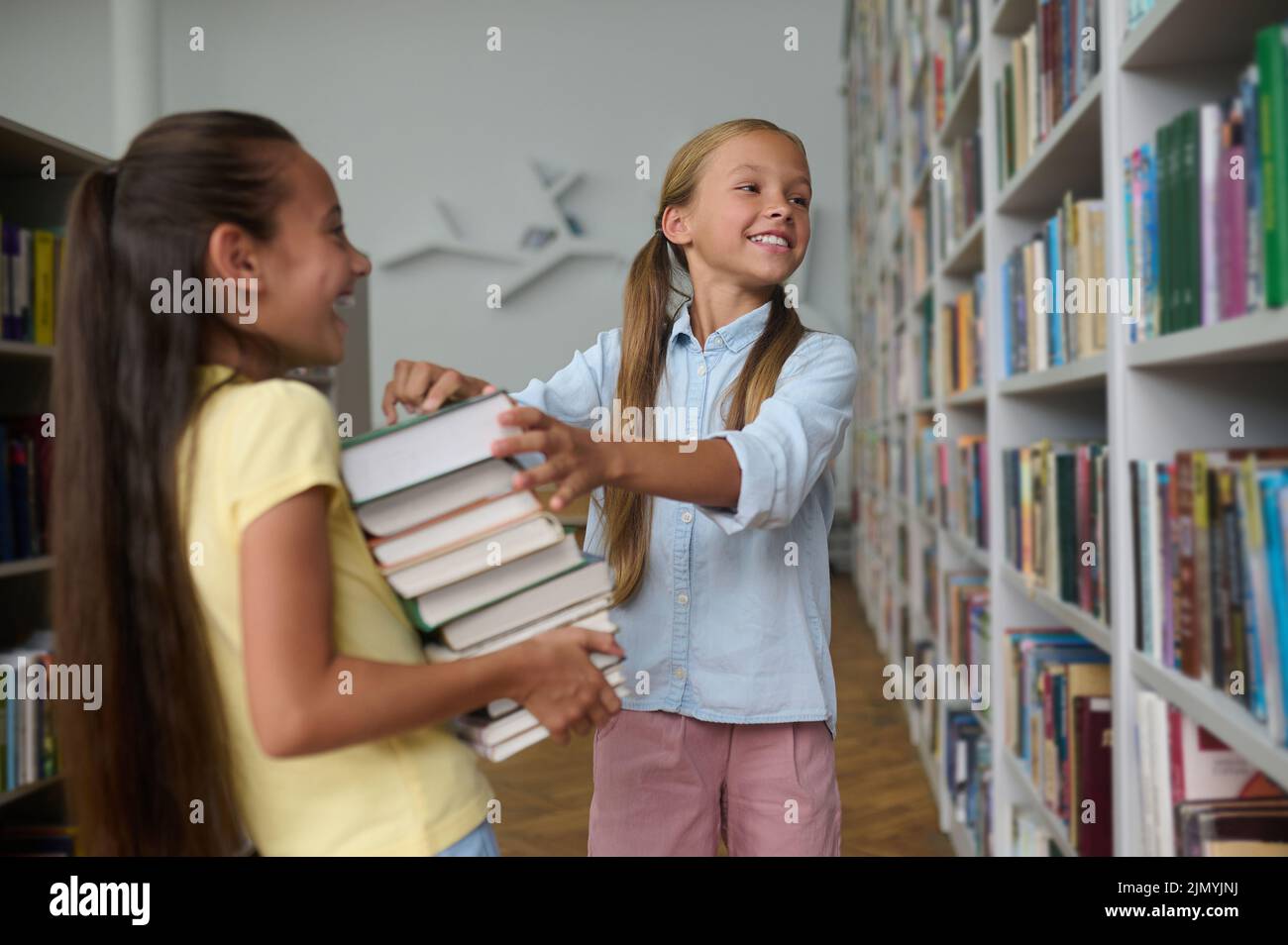 Deux écolières qui choisissent la littérature éducative dans la bibliothèque Banque D'Images