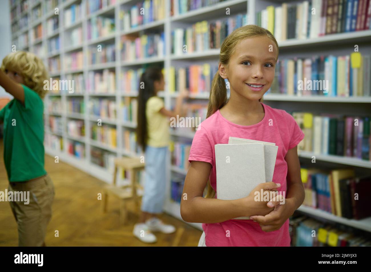 Trois enfants choisissent la littérature dans la bibliothèque Banque D'Images