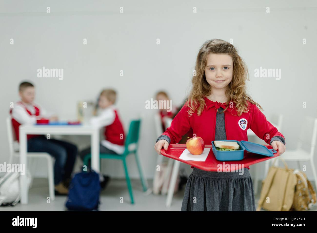 Happy School grirl dans un plateau de maintien uniforme avec déjeuner dans la cantine de l'école. Banque D'Images