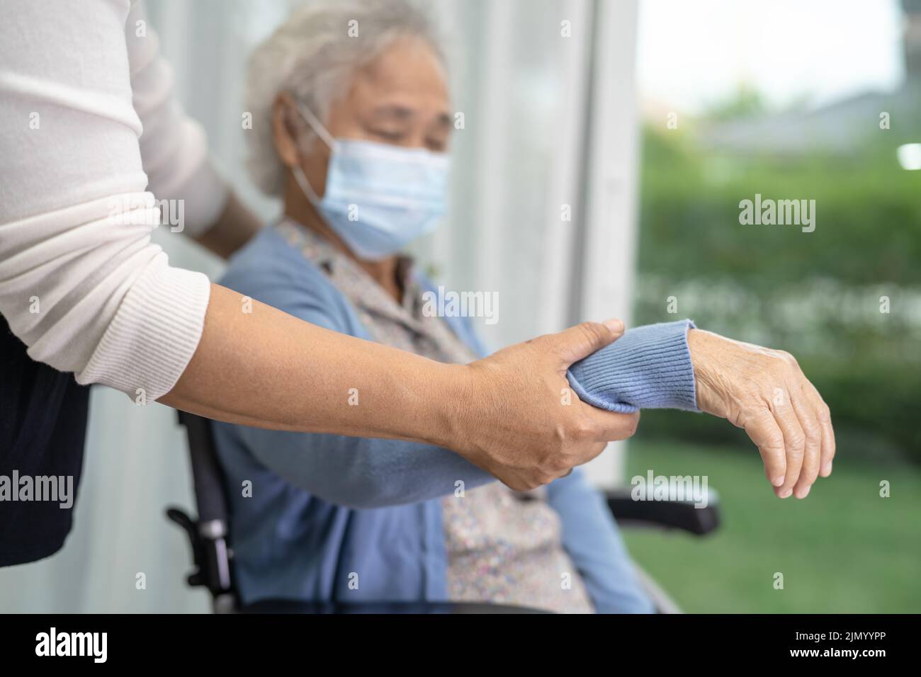 Aide asiatique senior ou âgée vieille femme assise sur un fauteuil roulant et portant un masque facial pour protéger l'infection de sécurité Covid19 coronavirus. Banque D'Images