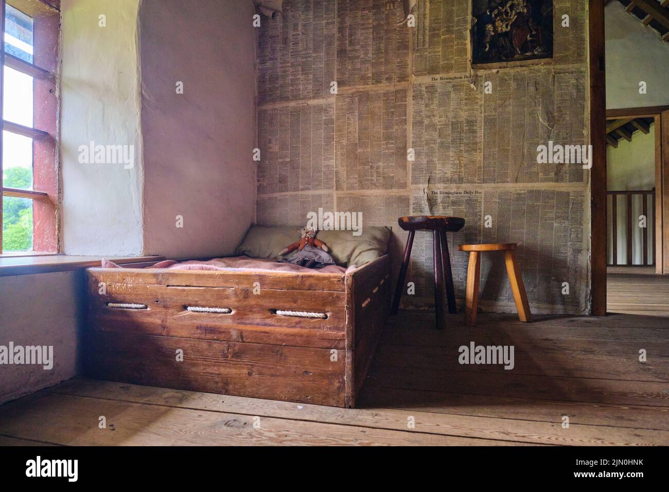 Un lit d'enfant fait maison avec un jouet de poupée de chiffon. Papier peint du journal. Dans une récréation d'une maison de travailleur typique, maison de Blaenavon Ironworks en BL Banque D'Images