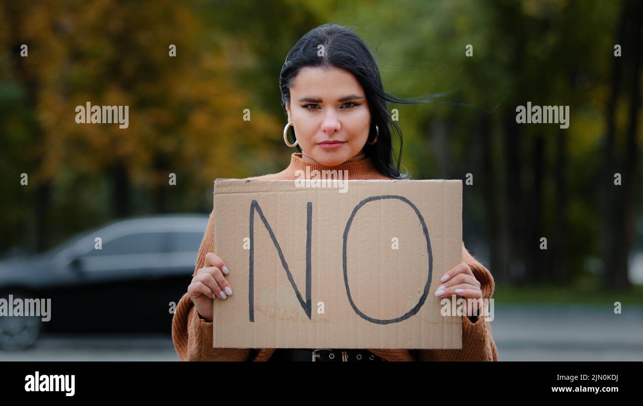 Une jeune fille de protestation en gros plan debout à l'extérieur regardant un appareil photo tenant une bannière en carton AUCUN membre de la communauté contre la violence domestique discrimination raciale Banque D'Images