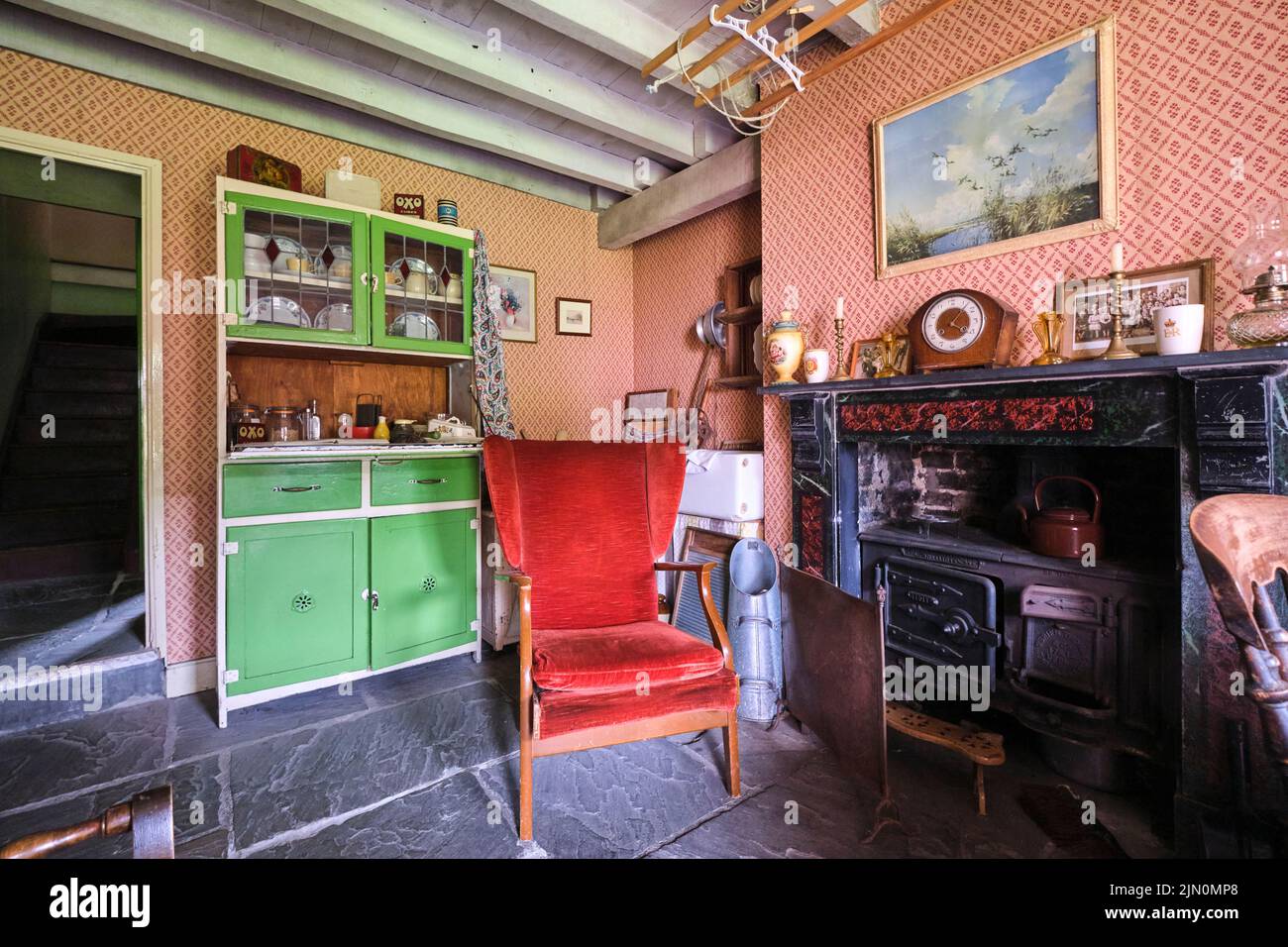 La salle de séjour avec cuisinière en fer forgé dans la cheminée, une alcôve avec évier de cuisine et une armoire à vaisselle verte. Dans une récréation d'un typique, gen Banque D'Images