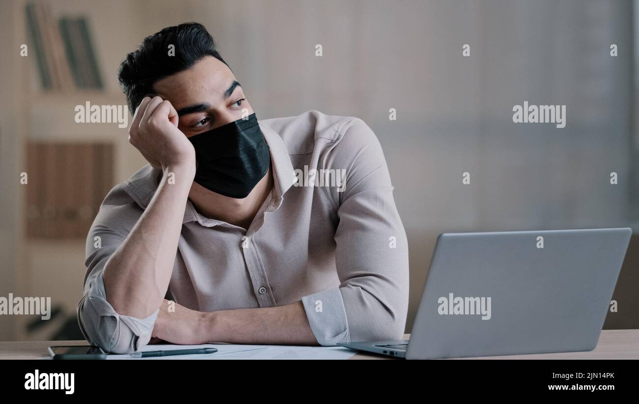 Ennuyé triste travailleur hispanique jeune homme d'affaires dans le masque médical fatigué employé non motivé désintéressé par le travail distant terne sur ordinateur paresseux homme arabe Banque D'Images