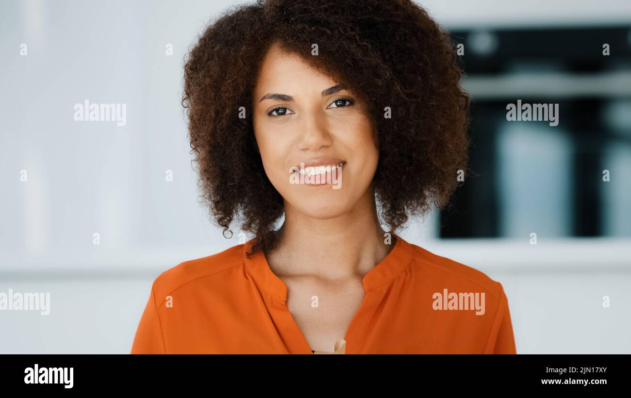 Souriant Afro-américaine fille avec cheveux bouclés maintenant donner cadeau montrant boîte cadeau emballé dans le papier rouge avec le ruban doré voeux joyeux anniversaire Banque D'Images