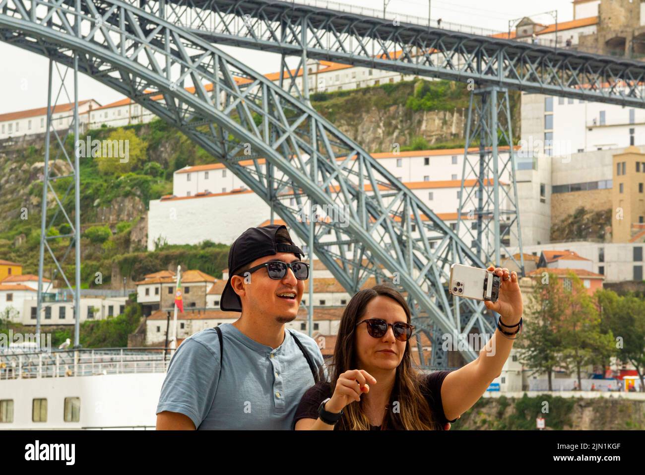 Couple prenant des selfies près du pont Luiz 1 pont au-dessus du fleuve Douro Porto Portugal qui a été conçu par Theophile Seyrig un partenaire de Gustave Eiffel Banque D'Images