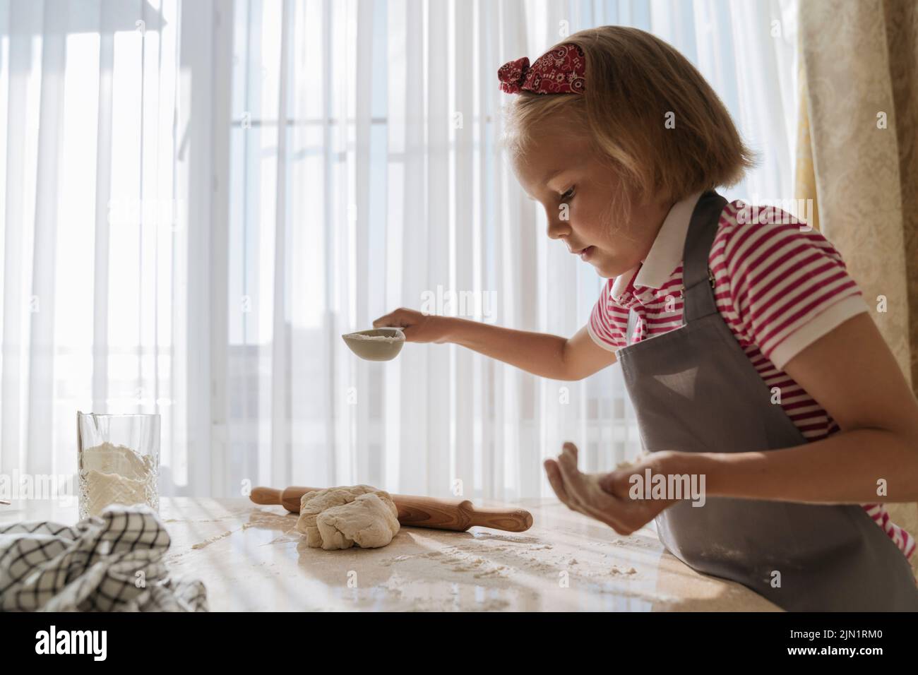 La fille de la cuisine cuisine de la pâte et de la farine. Banque D'Images