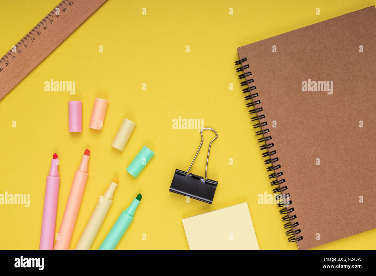 Carnet, crayons de couleur, papier note et pince, règle. Retour à l'école. Arrière-plan jaune isolé Banque D'Images