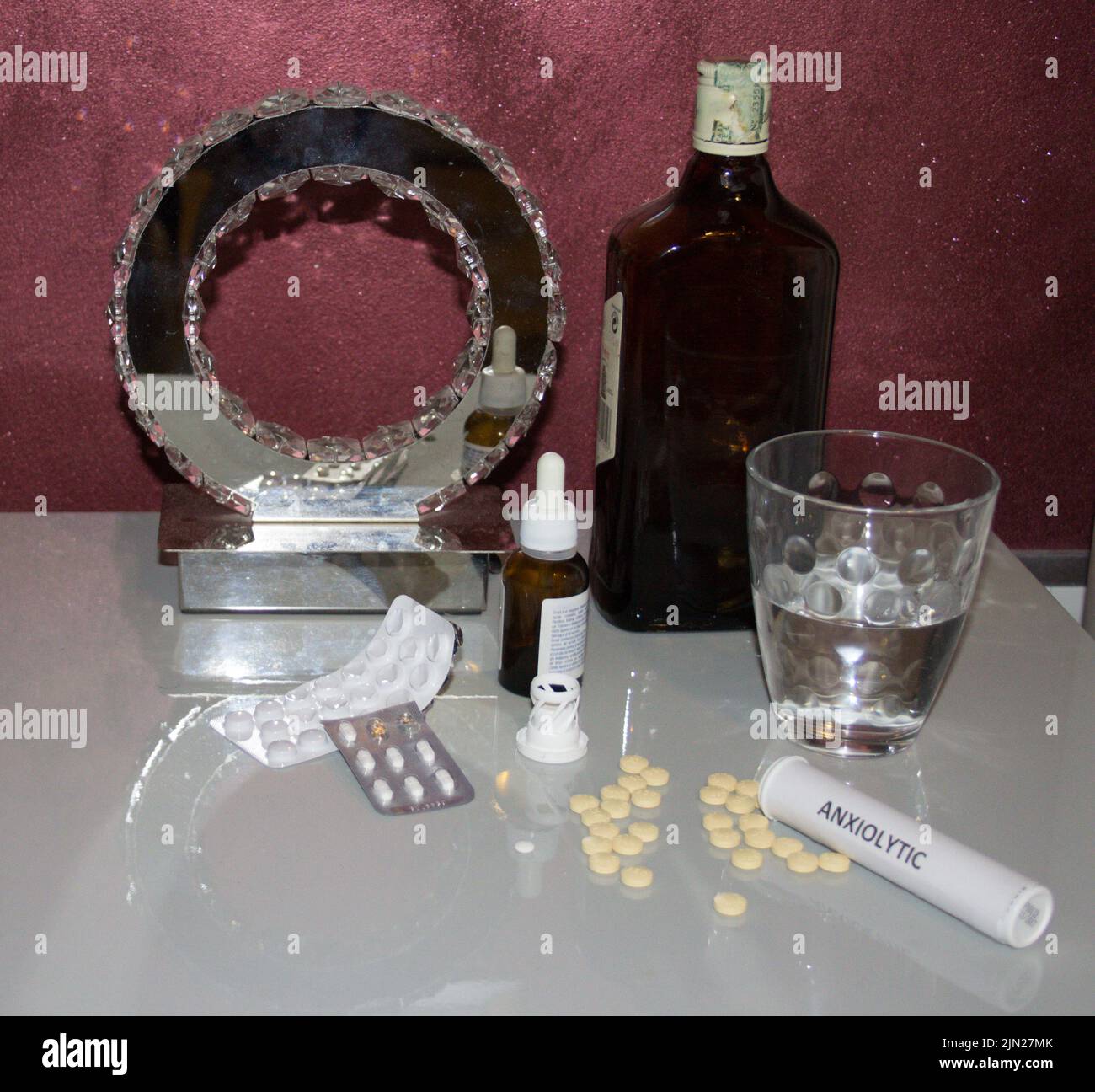 Image d'une table de chevet avec divers médicaments tels que des anxiolytiques et des antidépresseurs, un verre d'eau et une bouteille de whisky. Référence Banque D'Images