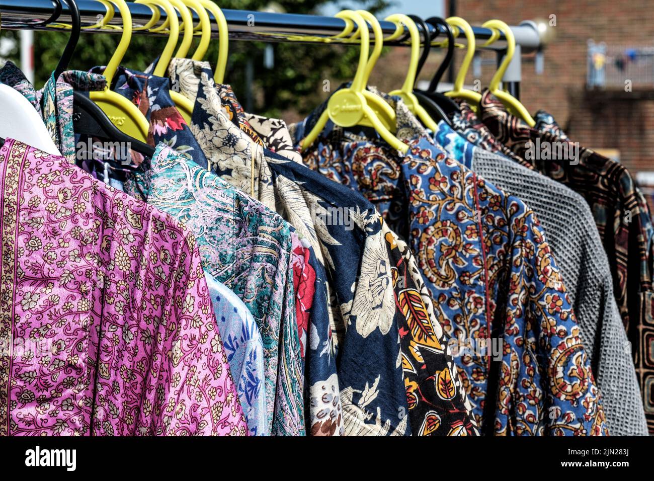 Dorking, Surrey Hills, Londres, Royaume-Uni, 07 juillet 2022, robes pour femmes colorées et lumineuses suspendues dans un marché extérieur tout en l'absence de personne Banque D'Images