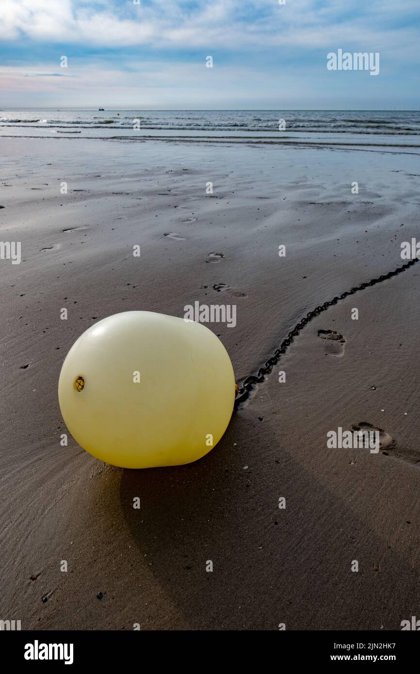 Bouée blanche sur une chaîne avec réflexion sur une plage à marée basse à Blankenberge, Belgique. Photo de haute qualité Banque D'Images