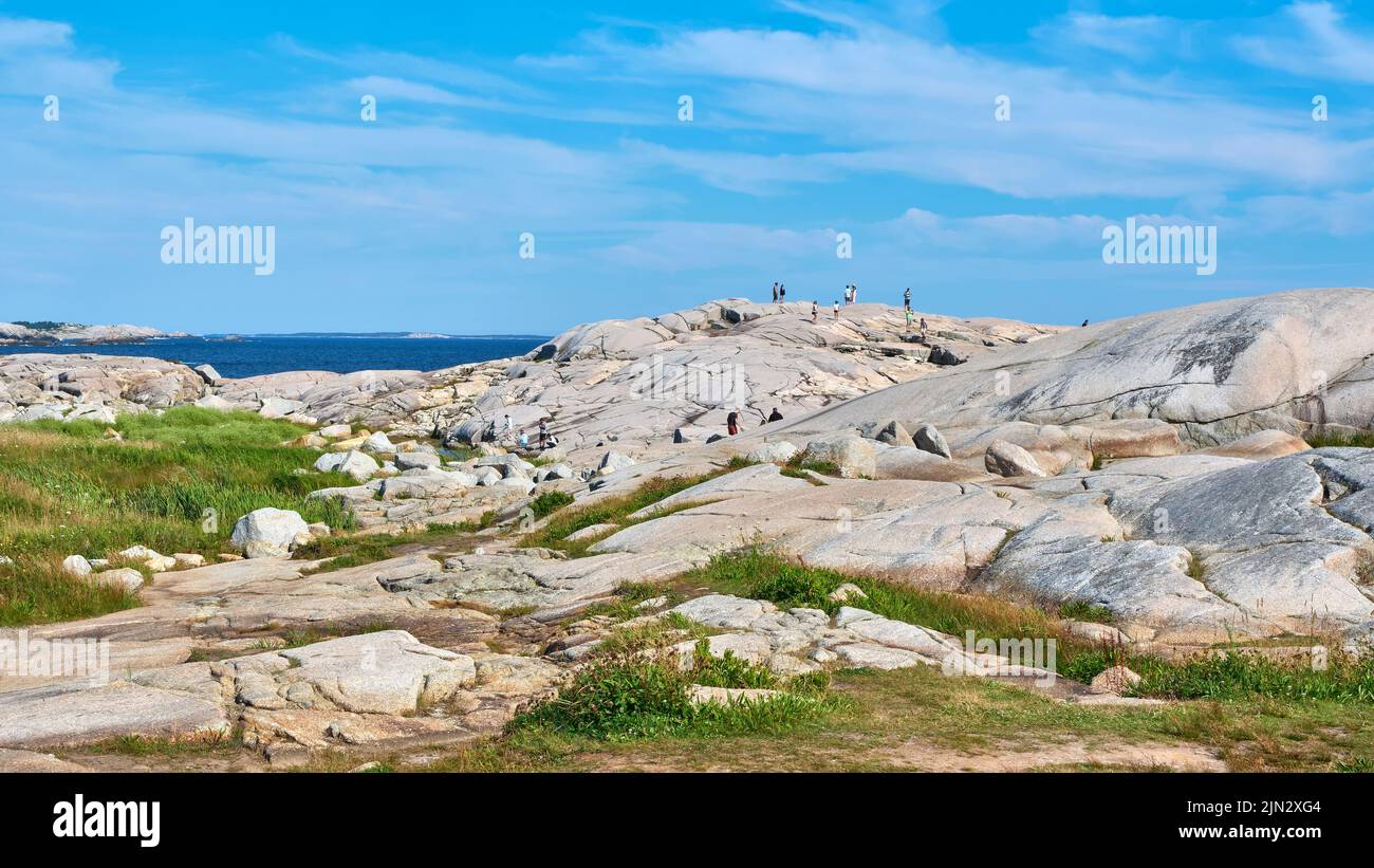 Les visiteurs sont éclipsés par les énormes rochers en granit de Peggy's Cove, en Nouvelle-Écosse. Banque D'Images