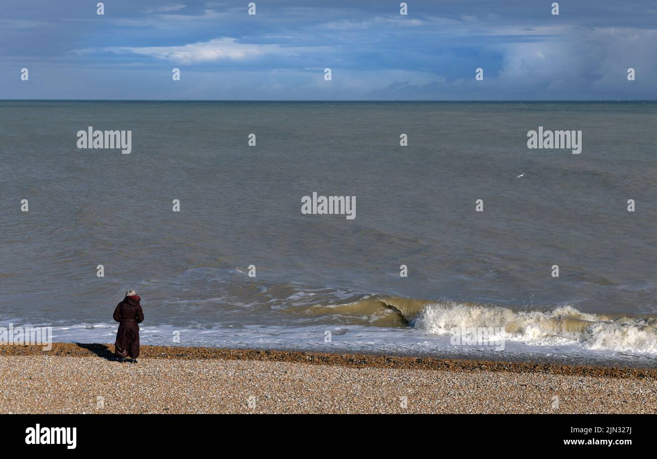 femme solitaire âgée regardant la chaîne anglaise à dungeness kent angleterre Banque D'Images