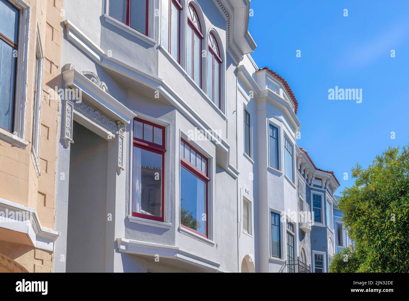 Rowhouses vue latérale avec murs peints sur les arbres contre le ciel à San Francisco, CA. Extérieur de bâtiments résidentiels avec garnitures décoratives Banque D'Images