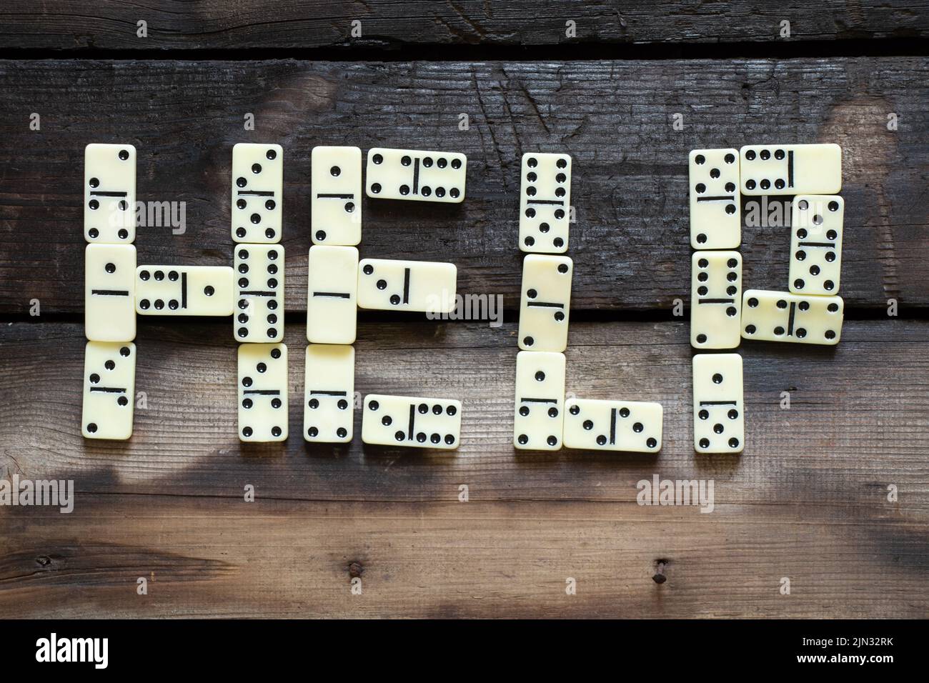 Le mot help est disposé à partir de lettres domino sur une ancienne table en bois de près Banque D'Images