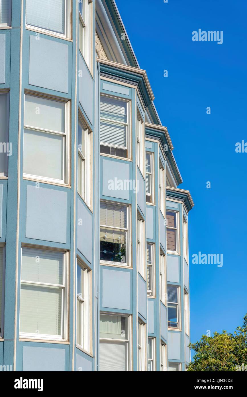 Immeuble d'appartements avec façade bleue et baies vitrées à San Francisco, Californie. Extérieur d'un appartement avec garnitures blanches et fenêtre en verre transparent p Banque D'Images
