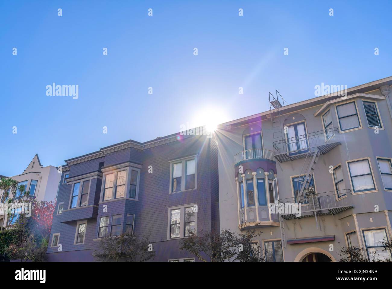 La lumière du soleil peeking entre les appartements violet et gris à San Francisco, CA. Appartement avec bardeaux en bois violet et fenêtres réfléchissantes à côté de la Banque D'Images