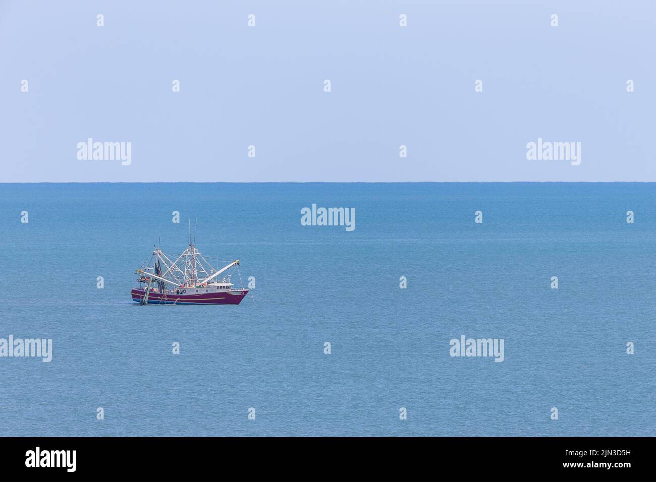 Bateau de pêche à la crevette commercial rouge sur la mer bleue. Les concepts pourraient inclure la pêche, l'agriculture, l'aquaculture, la nature, d'autres. Grand espace de copie si nécessaire Banque D'Images