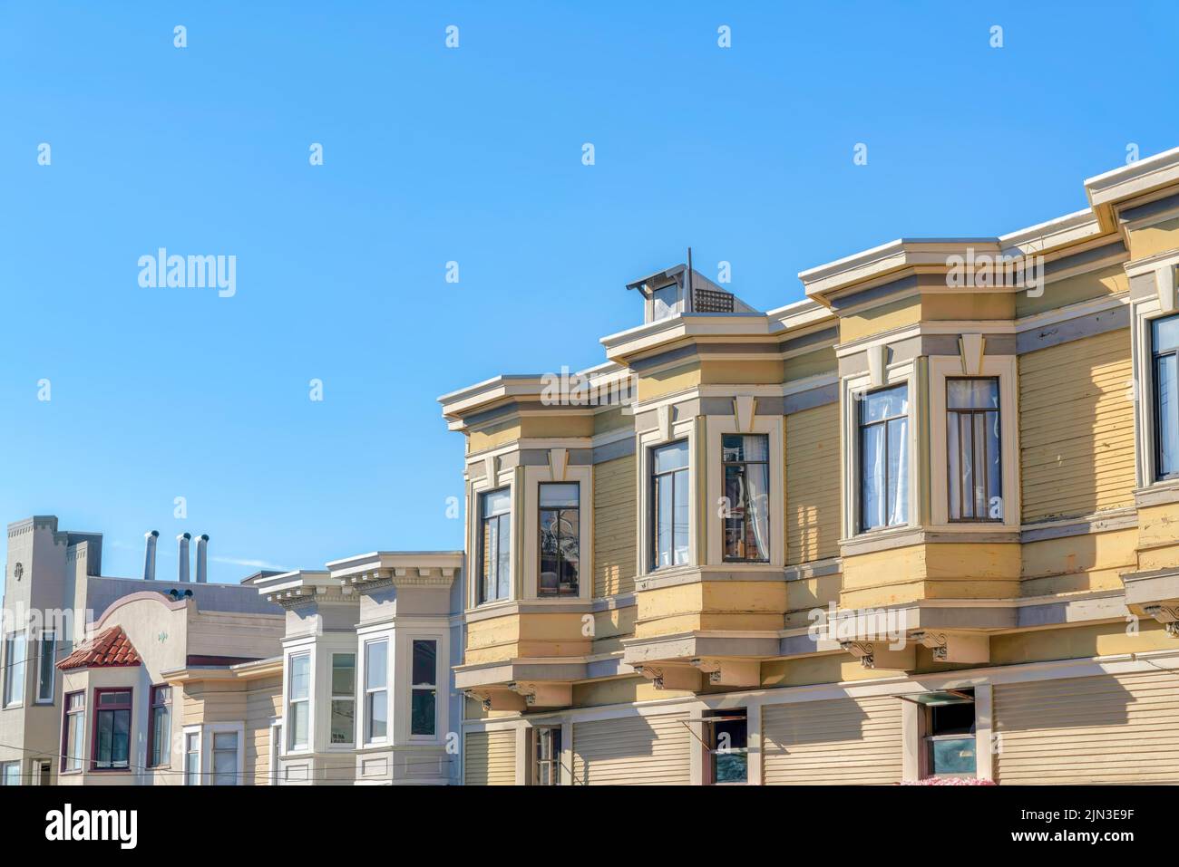 Rangée de maisons à San Francisco, Californie avec des bâtiments anciens et nouveaux. Il y a un appartement sur la droite avec une parement en bois jaune avec des intempéries Banque D'Images