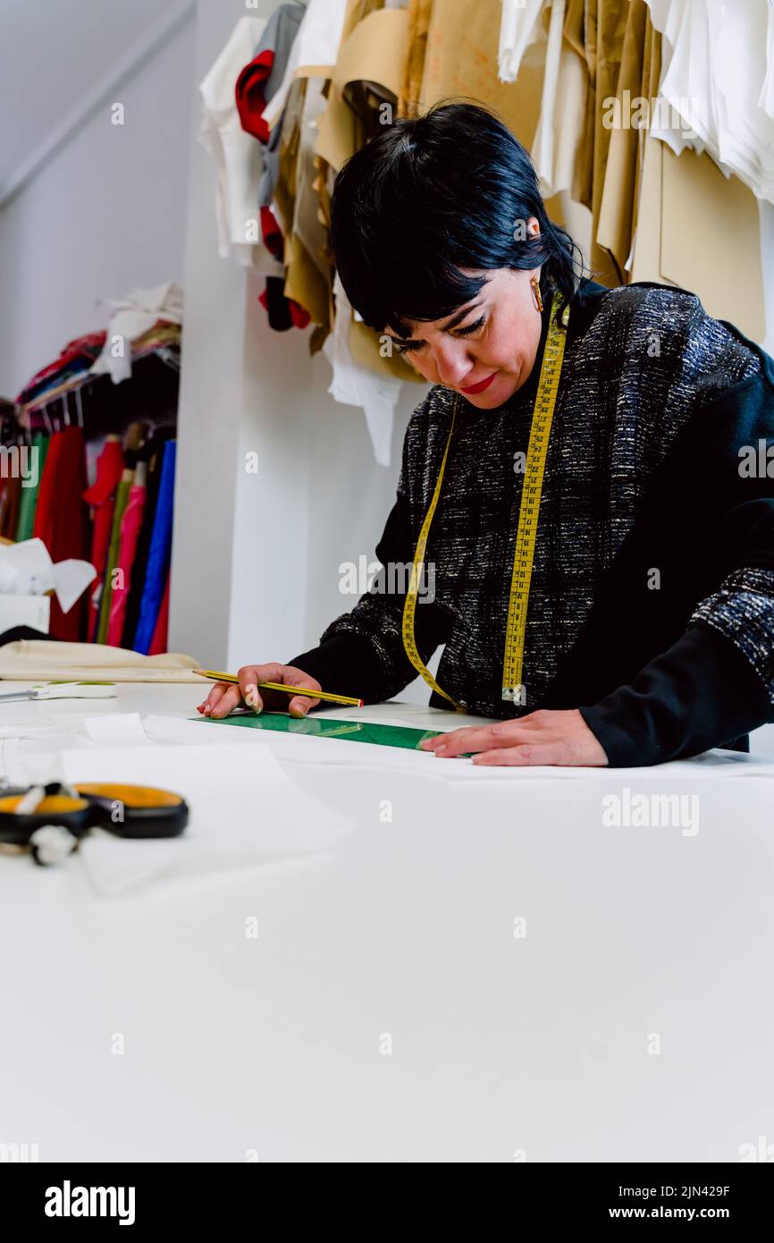 Couturière femme mesurant les vêtements pour les concevoir. Banque D'Images
