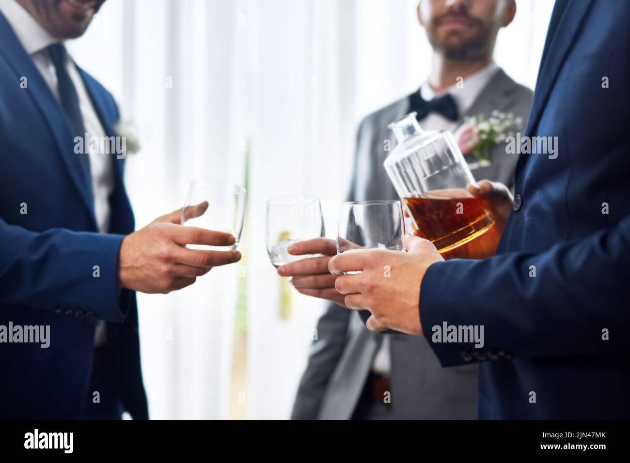 Partagez un verre en cette journée spéciale. Deux groommen méconnaissables partagent un toast avec le marié le jour de son mariage. Banque D'Images