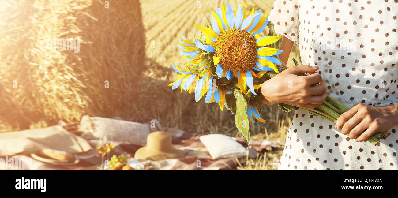 Jeune femme tenant un bouquet de tournesols aux couleurs du drapeau ukrainien dans le champ de blé Banque D'Images