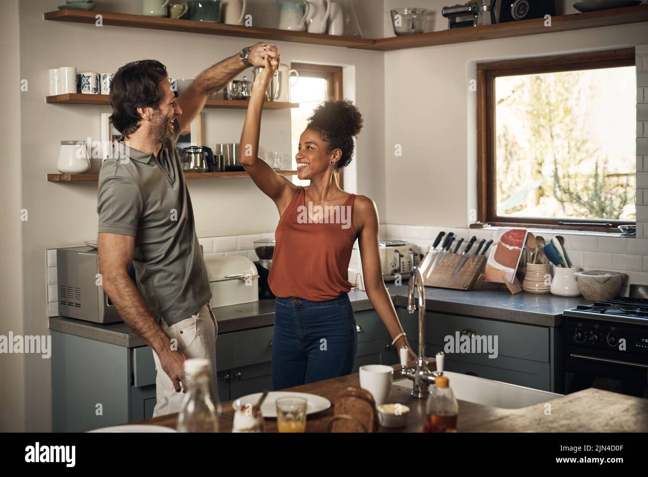 Vous me faites une fête. Un jeune couple affectueux dansant ensemble dans leur cuisine à la maison. Banque D'Images