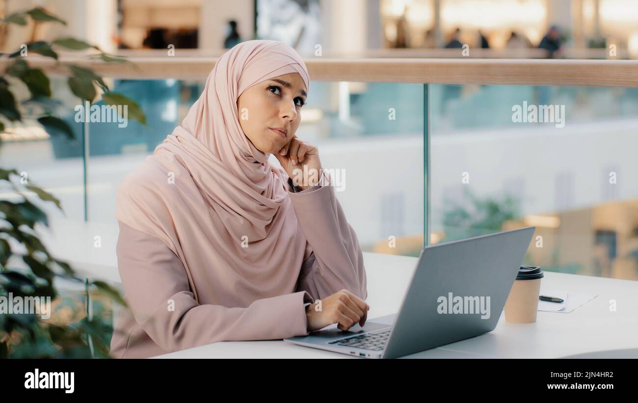 Pensive réfléchie inquiète jeune arabe femme écrivain travaillant sur ordinateur portable pense nouvelle idée démarrage développe plan écrit roman trouve la solution au problème Banque D'Images
