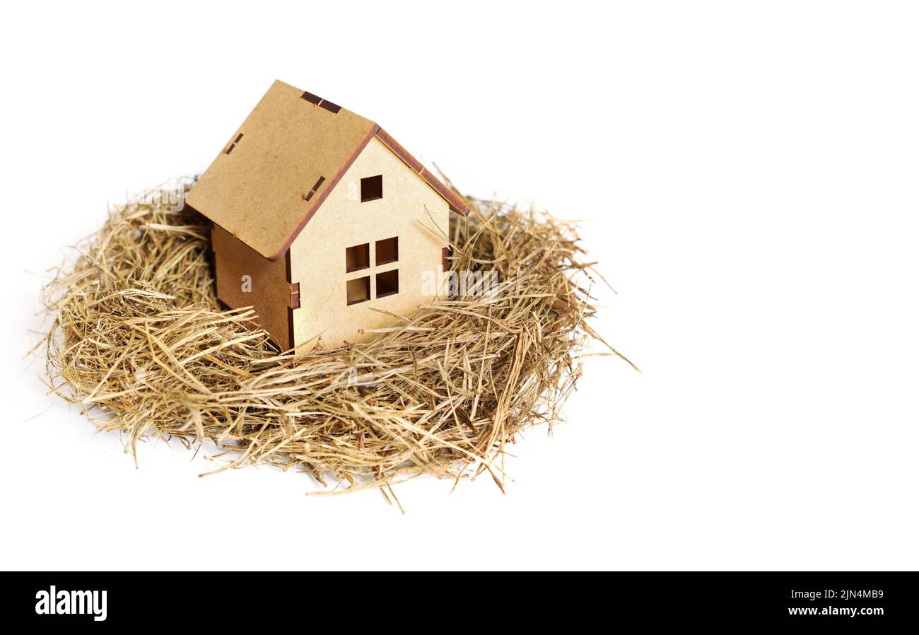 Modèle de maison en bois dans un nid d'oiseau isolé sur blanc. Concept de maison douce. Banque D'Images