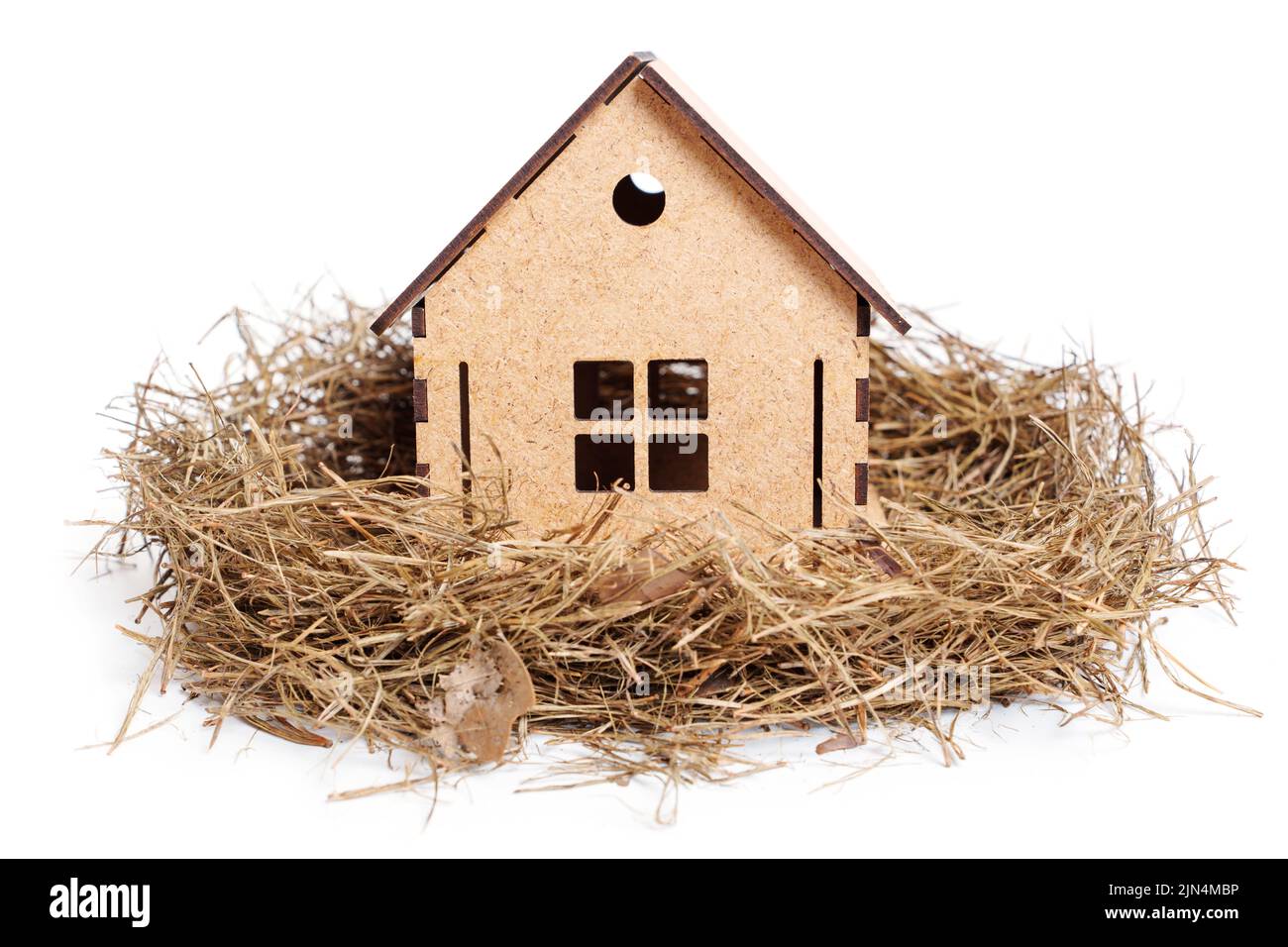 Nouvelle maison dans un nid de foin isolé sur fond blanc, gros plan. Faire de la maison un endroit sûr. Banque D'Images