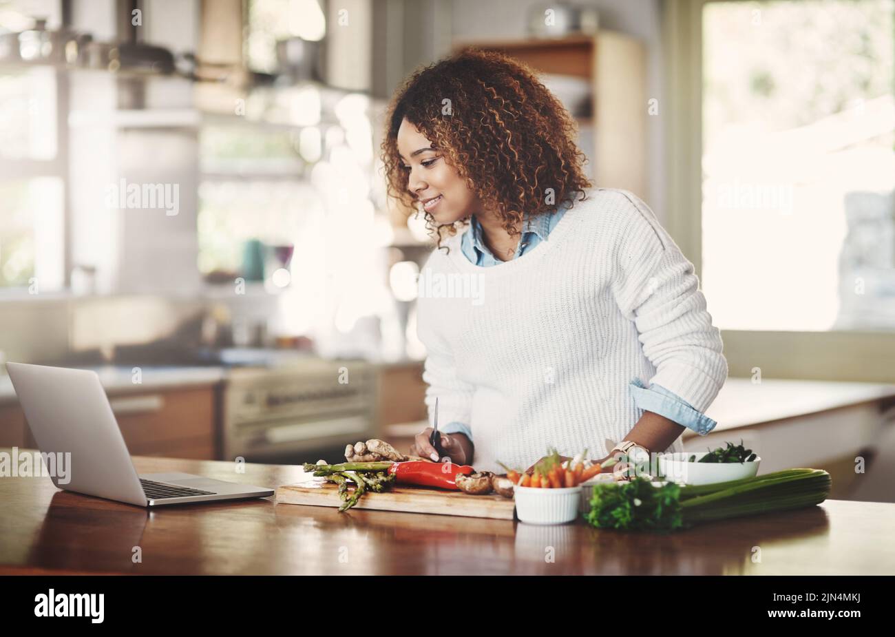 Femme préparant une nouvelle recette depuis Internet pour un dîner végétarien, un déjeuner ou un en-cas dans une cuisine à la maison. Un étudiant en cuisine ou en cuisine essayant un Banque D'Images