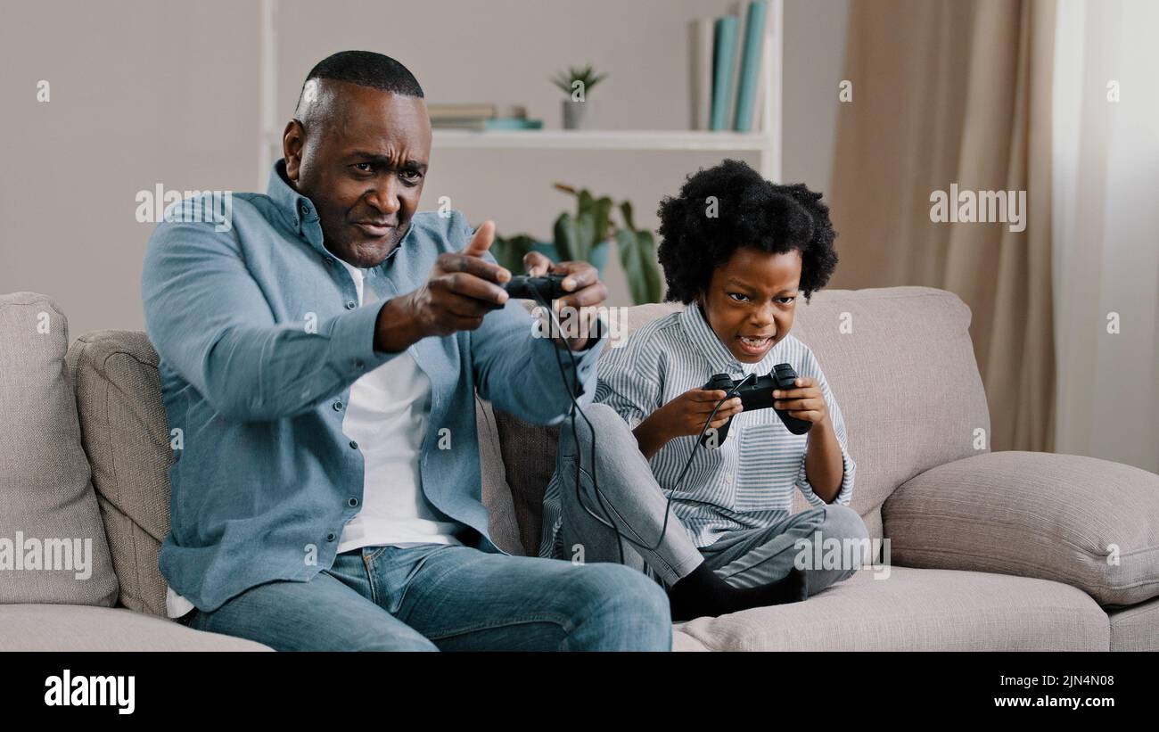 Heureux afro-américain famille papa et fille ont plaisir ensemble père jouant le jeu vidéo sur la console avec enfant fille utilisation contrôleur assis sur le canapé Banque D'Images